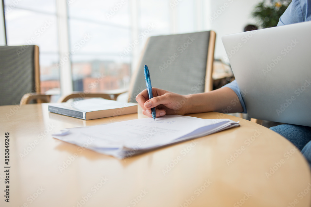 Womans hand taking notes in office Womans hand taking notes in office