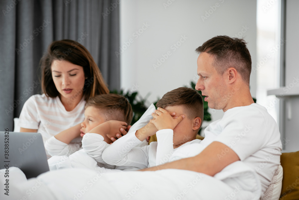 Beautiful parents with kids enjoying at home. Young family watching movie on lap top. Beautiful parents with kids enjoying at home. Young family watching movie on lap top.