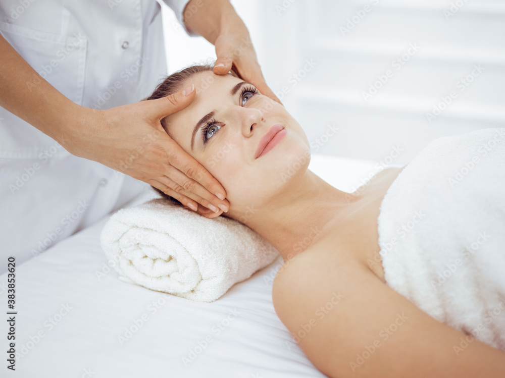 Young and blonde woman enjoying facial massage in spa salon. Beauty concept Young and blonde woman enjoying facial massage in spa salon. Beauty concept