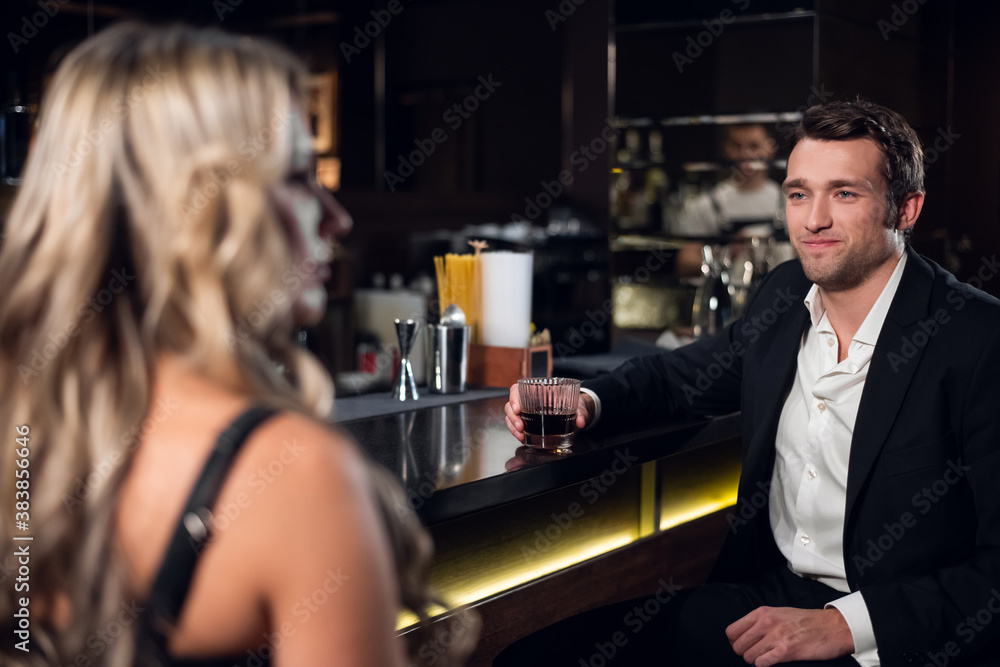 a young cute man tries to attract the attention of a beautiful blonde in a bar.