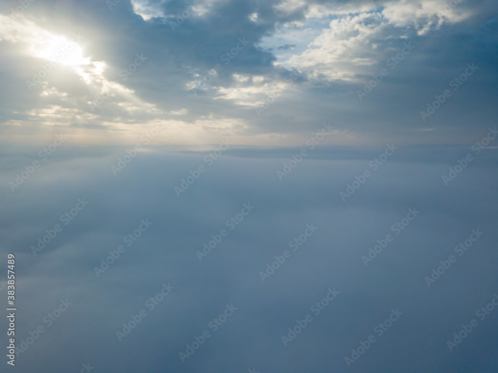 Aerial drone flight over the fog. There are thick clouds of fog below, the sun breaks through the clouds. Aerial drone flight over the fog. There are thick clouds of fog below, the sun breaks through the clouds.