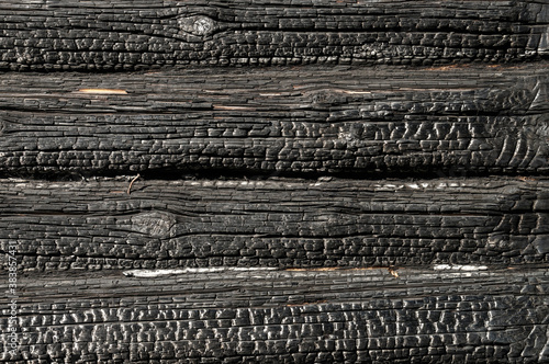 Texture (background, pattern) of a black charred log wall of a burned-out wooden house.