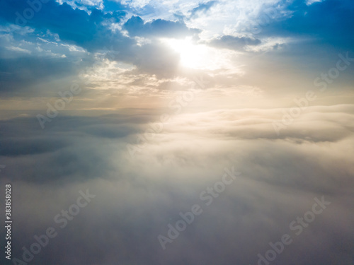 Aerial drone flight over the fog. There are thick clouds of fog below, the sun breaks through the clouds.
