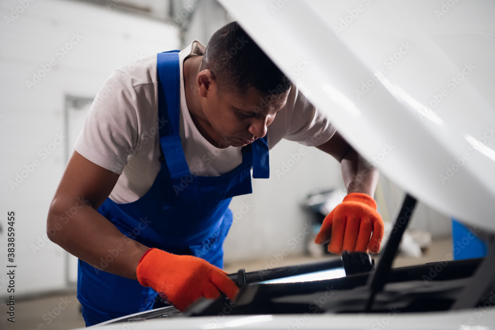 Uniform machinist uses a flashlight to inspect a car engine Uniform machinist uses a flashlight to inspect a car engine