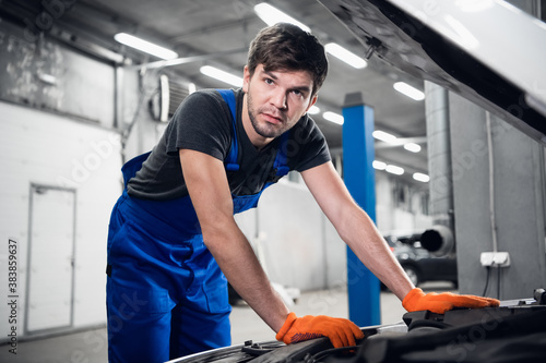 The man opened the hood of the car and checks the engine