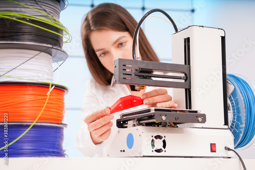 Obraz na płótnie Young female designer working on a prototype device on a 3D printer
