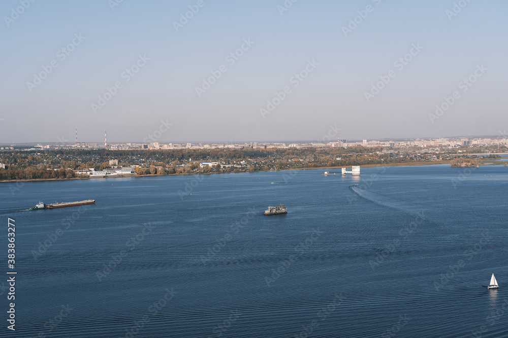Top view on the river and cityscape . Ferry boats, barges and cargo ships sailing on water. Daytime riverscape  image.