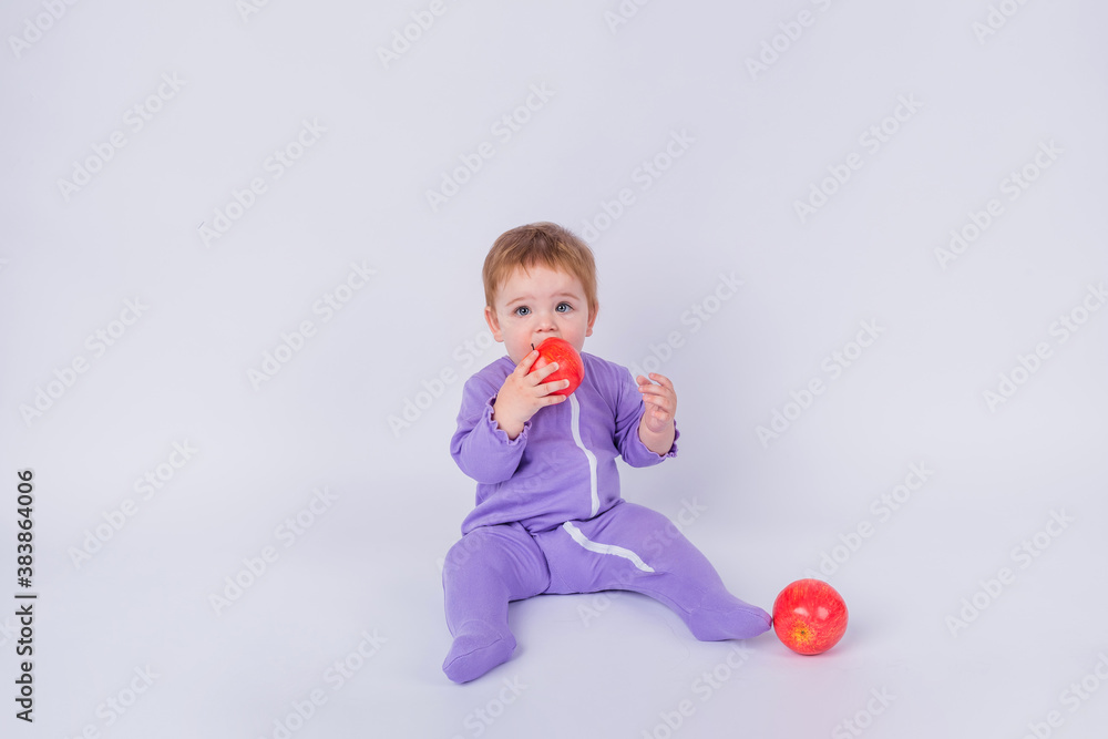 little baby girl in a purple jumpsuit with a red Apple on a white background little baby girl in a purple jumpsuit with a red Apple on a white background
