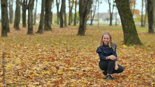 A teenage girl is sitting in an autumn park.