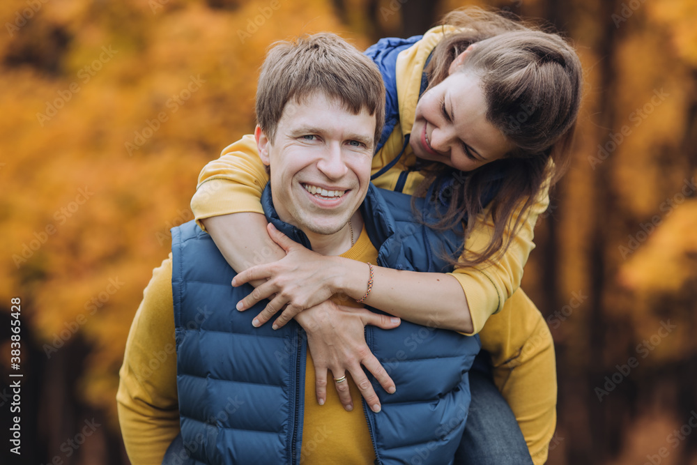 Portrait of a happy couple in autumn park, guy looking at camera and smiling