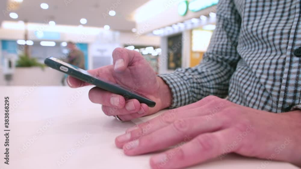 Close-up of a man's hands using the phone in a shopping mall. Transfer of information over a distance using the mobile Internet. Close-up of a man's hands using the phone in a shopping mall. Transfer of information over a distance using the mobile Internet.