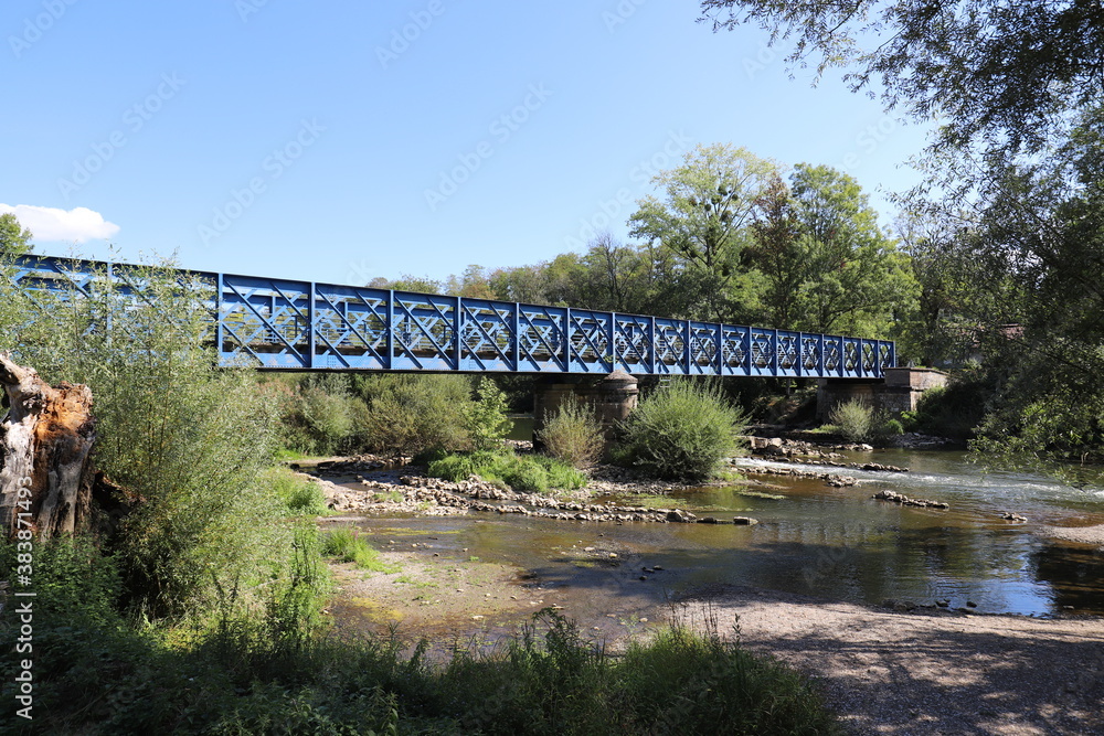 Beautiful old French railway bridge above a river. Photo was taken on a sunny day with an awesome blue sky.