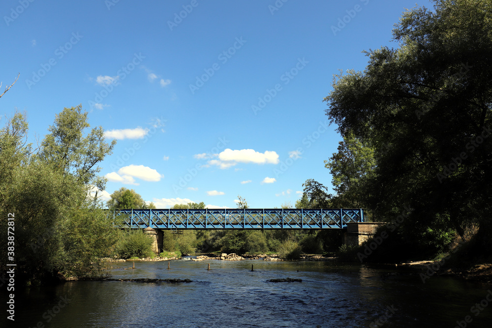 Beautiful old French railway bridge above a river. Photo was taken on a sunny day with an awesome blue sky.
