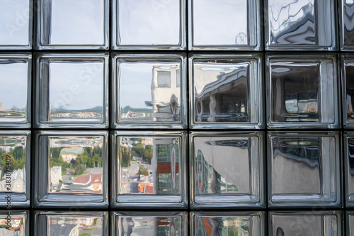 Distorted view of a town seen through glass blocks. Close up of glass wall allowing light to enter building interior.