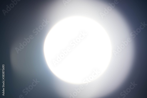 abstract white soft round light from flashlight glows to look like a full moon overlay on black background. Beam effect from flash of spotlight at night.