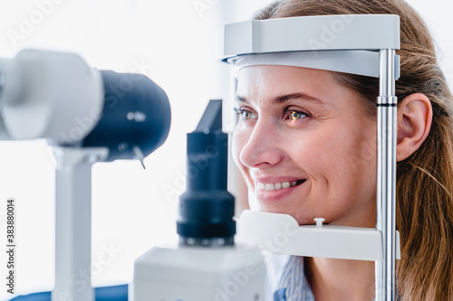 Close up photo of a smiling young woman patient during ophthalmic sight examination photo