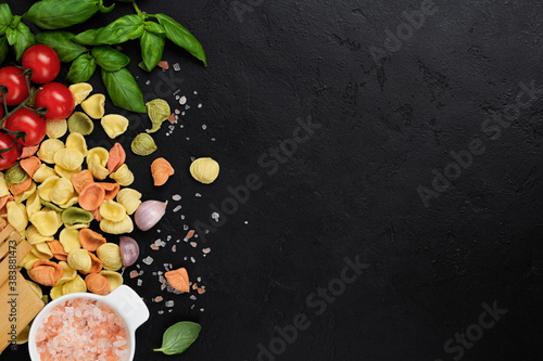 Italian Pasta orecchiette with traditional ingredients for the preparation food on black background. Culinary food cooking background. Top view.