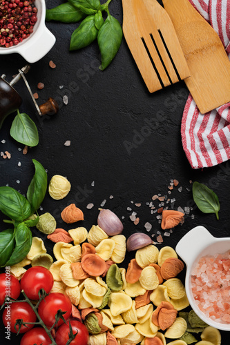 Italian Pasta orecchiette with traditional ingredients for the preparation food on black background. Culinary food cooking background. Top view.