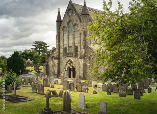 Front view of St. Canice's Cathedral in Kilkenny in Ireland with graves and headstones in the foreground.