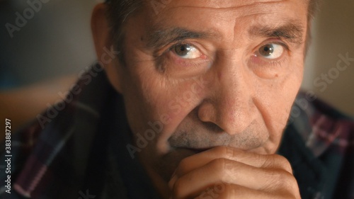 Serious elderly man thinking, looking at camera, closeup. Shallow DOF, 4K UHD.