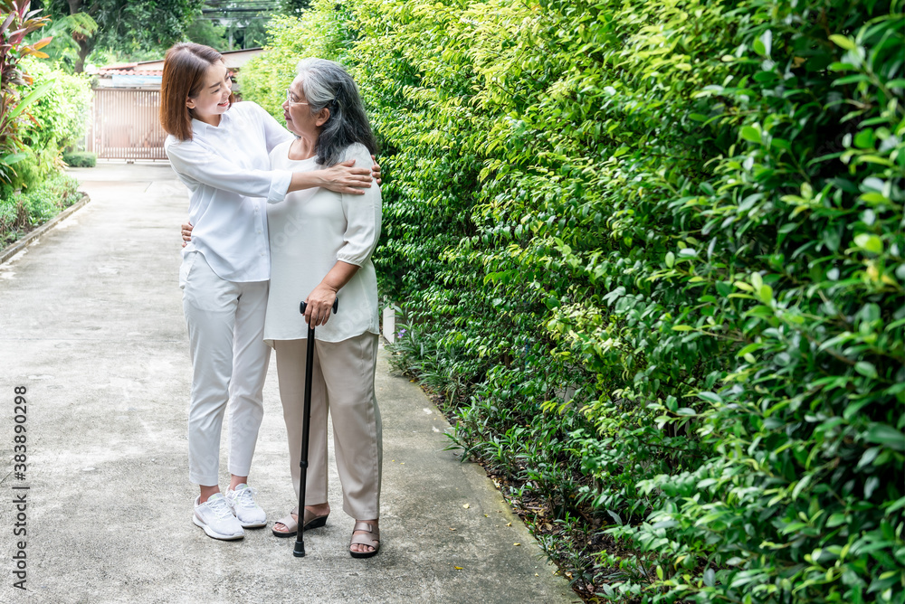 Fototapeta premium Portrait images of attractive Asian daughter embraced her elderly mother, who standing with cane And smile with happiness, to family and health care concept.