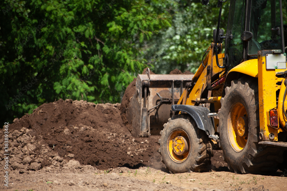 The excavator carries sand. Construction machinery on the street. Cleaning of sand with a bucket. The excavator carries sand. Construction machinery on the street. Cleaning of sand with a bucket.