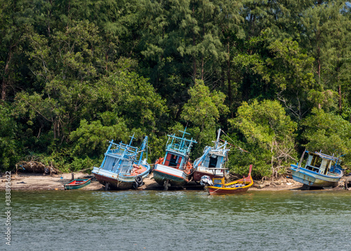 Fototapeta Naklejka Na Ścianę i Meble -  Abandoned fishing boats on the sandy beach near the rainforest