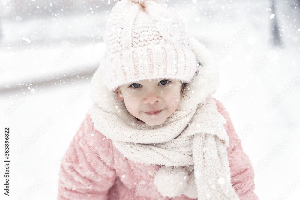 Happy baby girl rejoices in falling snow. Adorable smiling kid walks during snowfall. Happy baby girl rejoices in falling snow. Adorable smiling kid walks during snowfall.
