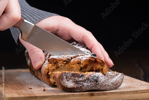 The girl cuts the raisin pie into pieces. Homemade cupcake on a wooden background.