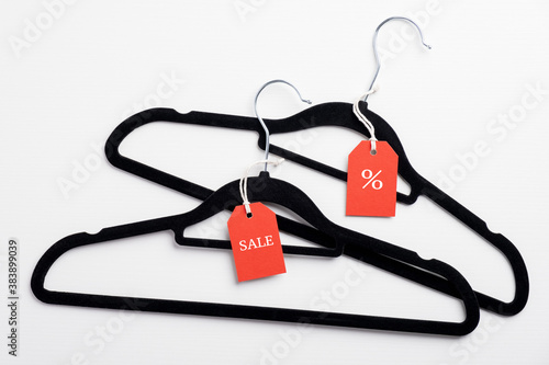 Two hangers with red tags on white background. Black Friday Sale concept. Flat lay, top view.