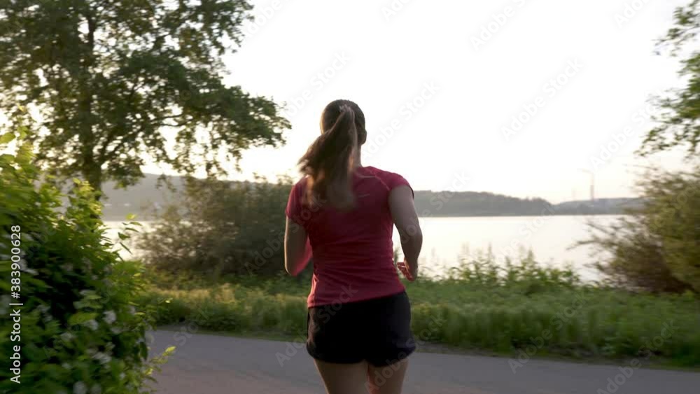 Person running in park street with trees at sunrise or sunset. Runner jogging in the morning. Road with sunlight. Outdoor leisure with fitness and endurance training in forest. Fit woman exercising. Person running in park street with trees at sunrise or sunset. Runner jogging in the morning. Road with sunlight. Outdoor leisure with fitness and endurance training in forest. Fit woman exercising.