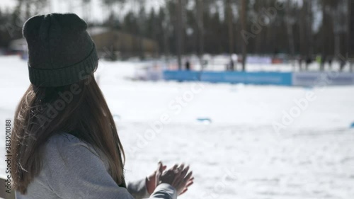 Fan cheering in skiing competition. Winter olympics or world championship event. Woman watching cross-country skier competing in stadium. Crowd supporting athlete.