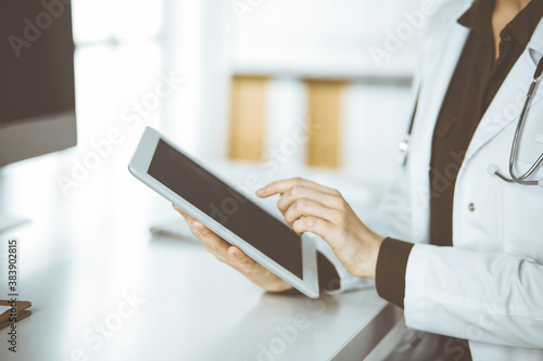 Unknown female doctor using tablet computer in clinic. Perfect medical service in hospital. Medicine concept