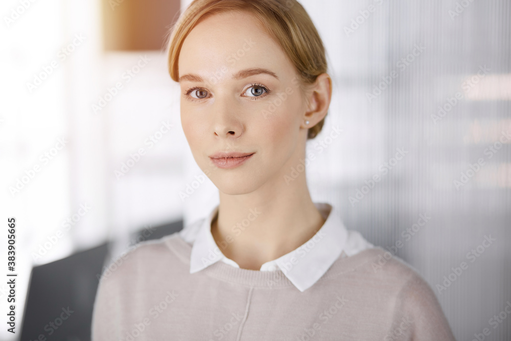 Friendly adult casual dressed business woman standing straight. Concept of a sunny business headshot or portrait in office Friendly adult casual dressed business woman standing straight. Concept of a sunny business headshot or portrait in office