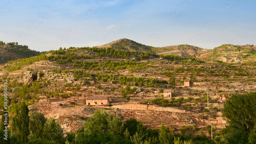 Picturesque rural landscape of earthy mountains with some rocks, old haystacks, agricultural terraces called bancales and scattered trees