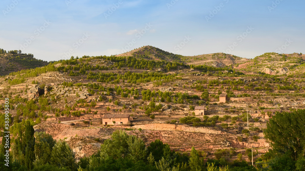 Picturesque rural landscape of earthy mountains with some rocks, old haystacks, agricultural terraces called bancales and scattered trees Picturesque rural landscape of earthy mountains with some rocks, old haystacks, agricultural terraces called bancales and scattered trees