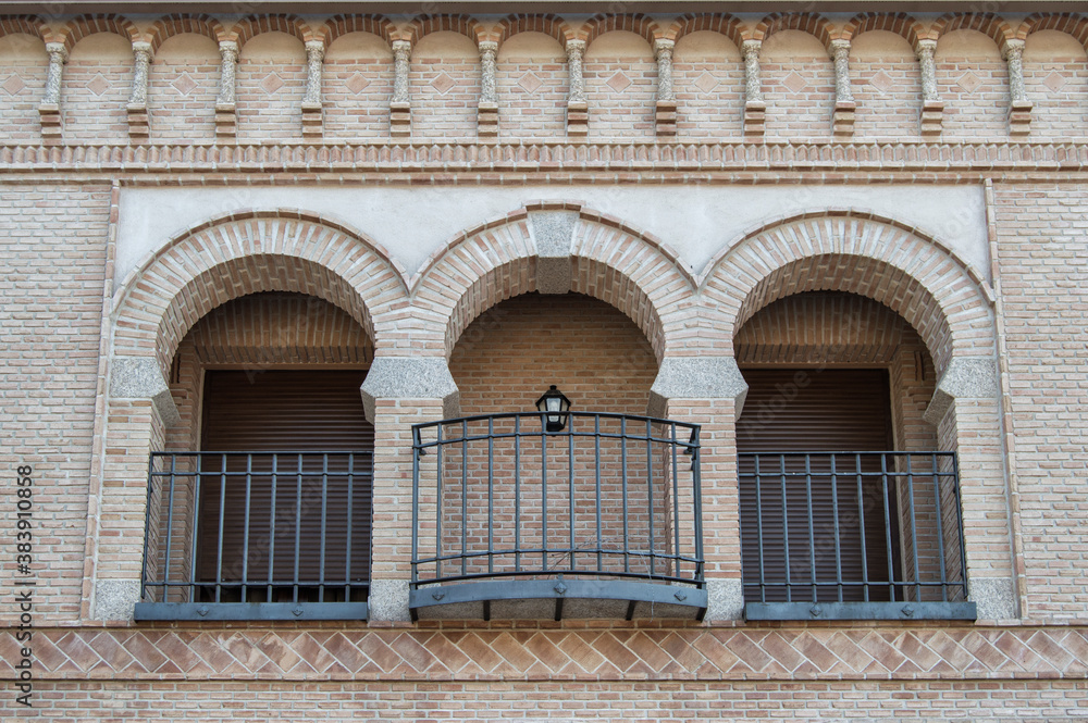 modern brick facade with three mudejar style arches on the balcony