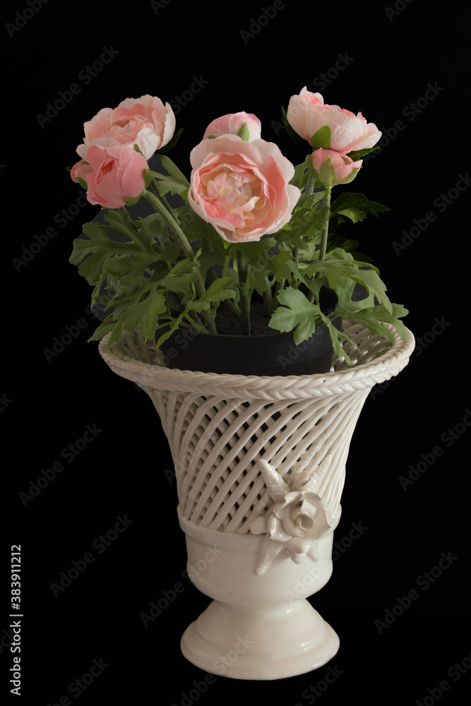white openwork ceramic cup with a pot with artificial pink buttercups white openwork ceramic cup with a pot with artificial pink buttercups