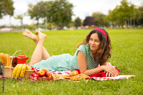 Beautiful young woman having picnic on sunny spring day in park © dragonstock