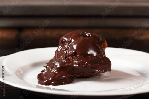 Choux pastry ball with custard filling and chocolate sauce icing photo
