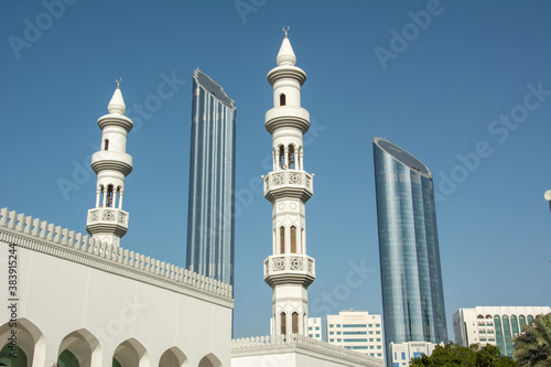 The view of modern skyscraper towers and white washed minarets of an old church in Abu Dhabi, United Arab Emirates