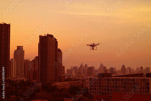 City at sunset with a frying drone in the golden orange sky