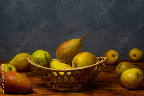 Fresh pears in a basket on a wooden table. Free space for an inscription.
