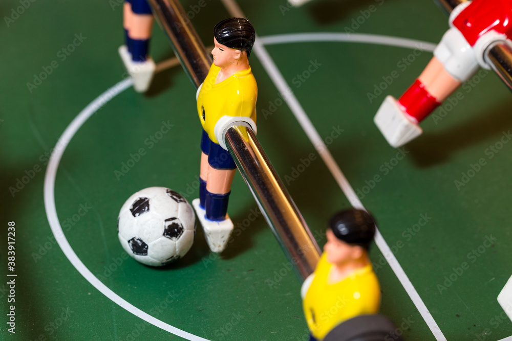 Detail of indoor table football, table soccer, or foosball, with midfielder and ball in the center. The opposing team jersey color is yellow vs. red. High side view Detail of indoor table football, table soccer, or foosball, with midfielder and ball in the center. The opposing team jersey color is yellow vs. red. High side view