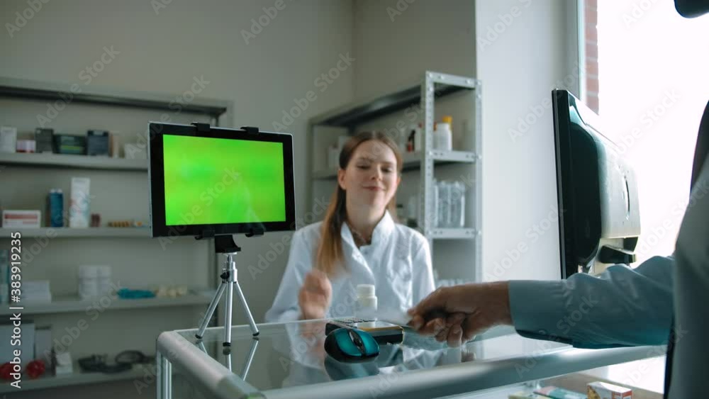 Customer is buying pills in drugstore. Green screen chromakeyed tablet PC ready for tracking. Caucasian woman is preparing terminal for credit card paying. Customer is buying pills in drugstore. Green screen chromakeyed tablet PC ready for tracking. Caucasian woman is preparing terminal for credit card paying.