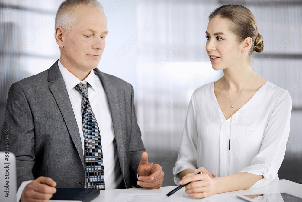 Elderly businessman and woman sitting and communicating in office. Adult business people or lawyers working together as a partners and colleagues at meeting. Teamwork and cooperation concept Elderly businessman and woman sitting and communicating in office. Adult business people or lawyers working together as a partners and colleagues at meeting. Teamwork and cooperation concept