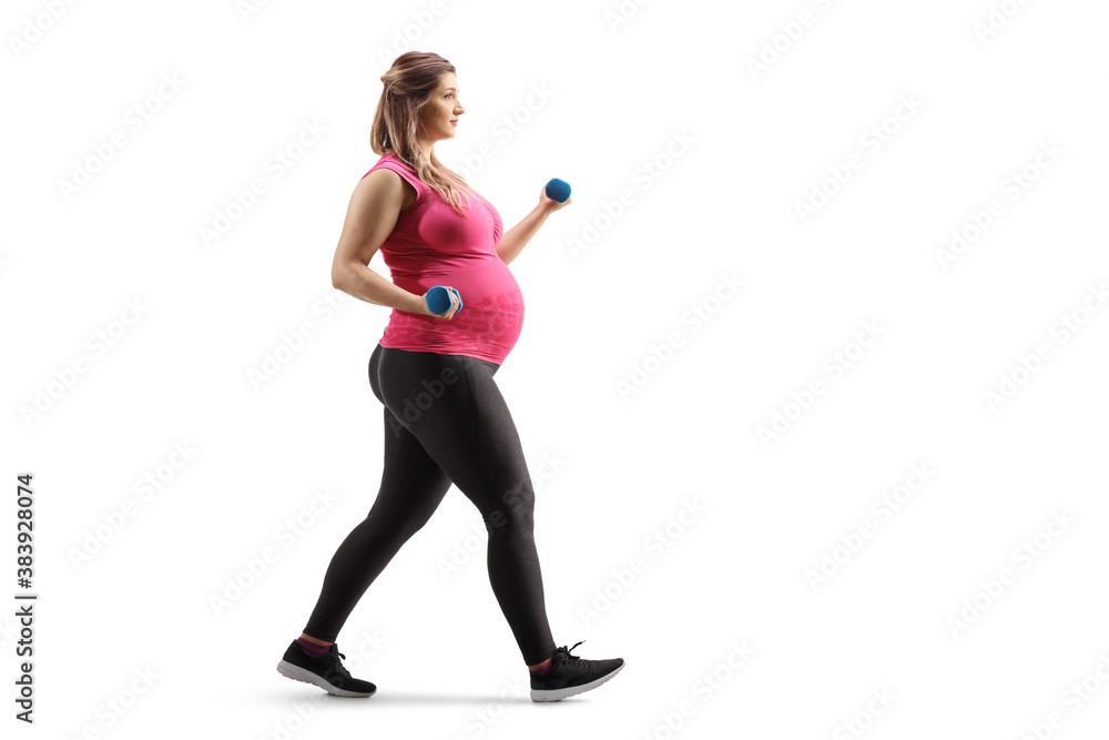 Full length profile shot of a pregnant woman walking and exercising with dumbbells Full length profile shot of a pregnant woman walking and exercising with dumbbells