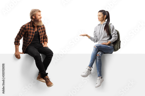 Bearded guy laughing and talking to a female student seated on a blank panel