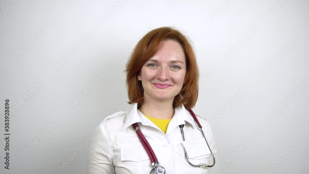 Young female doctor smiling. Portrait of a woman in a medical gown with a stethoscope around her neck.White background. 4k Young female doctor smiling. Portrait of a woman in a medical gown with a stethoscope around her neck.White background. 4k