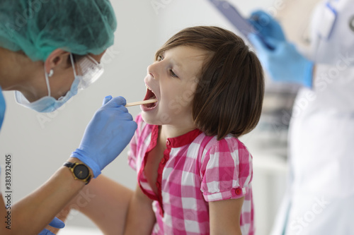 Little girl's throat is examined at doctor's appointment. Medical care for children and health examination concept